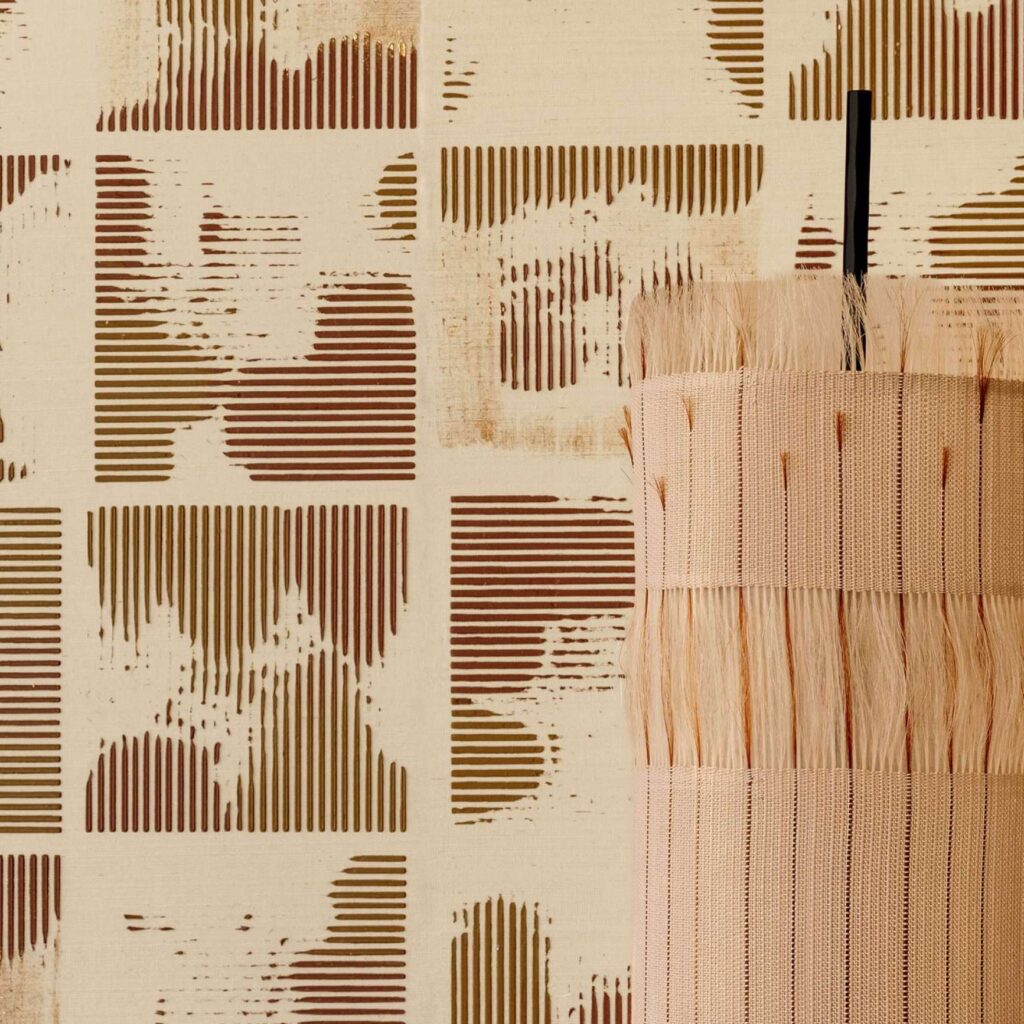 Beige en bruin gestreept Elitis Maestria Kalliste RM 1077-02 behang met decoratief rietobject op de voorgrond.