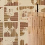 Beige en bruin gestreept Elitis Maestria Kalliste RM 1077-02 behang met decoratief rietobject op de voorgrond.