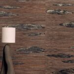 Moderne interieursetting met Elitis Maestria Orion RM 1076 80 behang in bruin- en goudtinten en een beige vloerlamp.