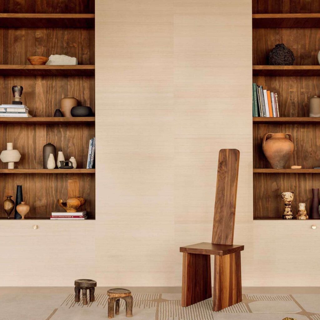 Minimalistisch interieur met Elitis Maestria Pur Abaca wandbekleding, houten meubels en decoratieve aardewerken objecten.