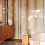 Sfeervolle badkamer met Elitis Maestria Tissoro RM 1078 01 behang, houten meubels en een vrijstaand bad.