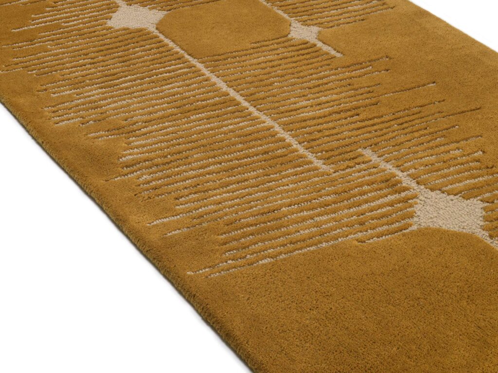 Detail van de Elitis Marcel TA 134 25 06 vloerkleedloper met een geometrisch patroon in okergeel en beige.