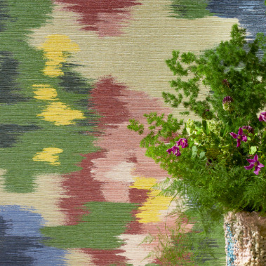 Abstract bloemrijk Elitis-behang met kleurrijk vervagend patroon en een vaas met paarse bloemen op de voorgrond.