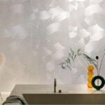 Moderne badkamer met Elitis Matières à Réflexions Circolo VP 976 02 behang en minimalistisch wastafelblad met decoratieve vazen.