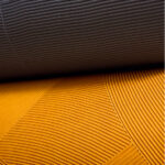 Detailopname van Elitis Circolo VP 976 wandbekleding met reliëfstructuur in grijs en okergeel.