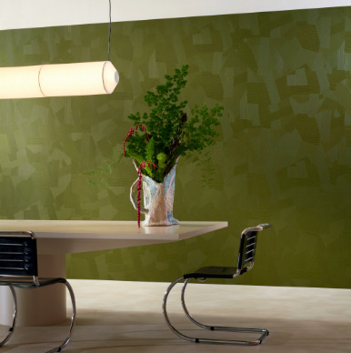 Modern interieur met Elitis Matières à Réflexions Dédales VP 975 60 behang in groen, met designmeubels en een vaas met bloemen op een tafel.
