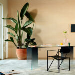 Modern interieur met een glazen bureau, designstoel, groot kamerplant en Elitis Equilibre VP 977-02 wandbekleding.