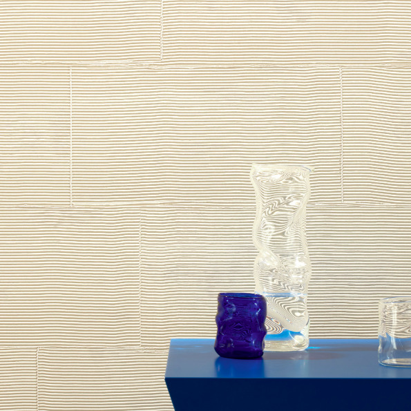 Glazen decoratieve vazen op een blauw oppervlak voor een Elitis Équilibre wandbekleding met golvend lijnpatroon.