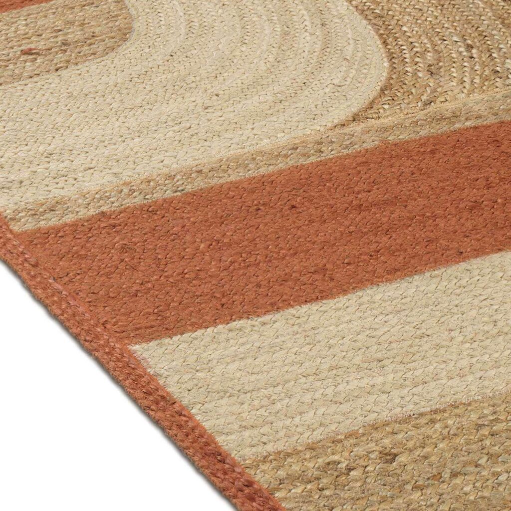 Detail van het Elitis Penny Lane TA 119 35 04 vloerkleed met geweven structuur en aardetinten in banen en gebogen patronen.