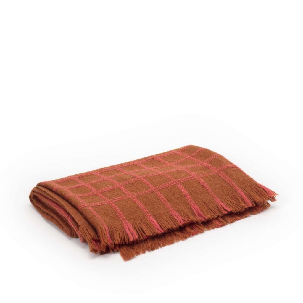 Opgevouwen Elitis plaid Edith PL 307 36 02 in bruin met roze ruitpatroon en franjes.