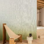 Minimalistisch interieur met Elitis Poesies de l’Instant behang in groenverloop, houten loungestoel en marmeren bijzettafeltje.