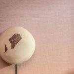 Roze Elitis Poesies de l’instant RM 1082 13 behang met decoratief object op een standaard.