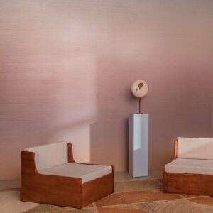Twee houten loungestoelen en een beeld op sokkel staan in een interieur met Elitis Poesies de l’Instant RM 1082 13 behang in zachte roze tinten.