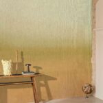 Modern interieur met Elitis Poesies de l’Instant RM 1082 14 behang in aardetinten en decoratieve accessoires op een houten tafel.