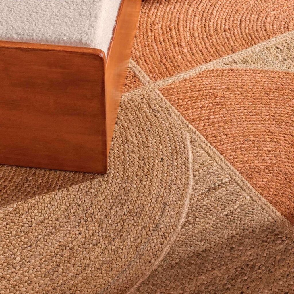 Detail van het Elitis Rocky PF TA 109 35 04 vloerkleed met een geometrisch patroon in aardetinten naast een houten meubelstuk.