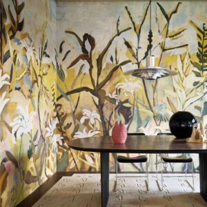 Eetkamer met het Elitis Sangpi L’Eden et Après VP 1027-01 bloemenpatroon op de muur en moderne decoratie op een donkere houten tafel.