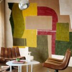 Sfeervol interieur met leren stoelen en Elitis Sangpi Terres Lointaines VP 1019-01 wandbekleding met abstract geometrisch patroon in aardetinten.