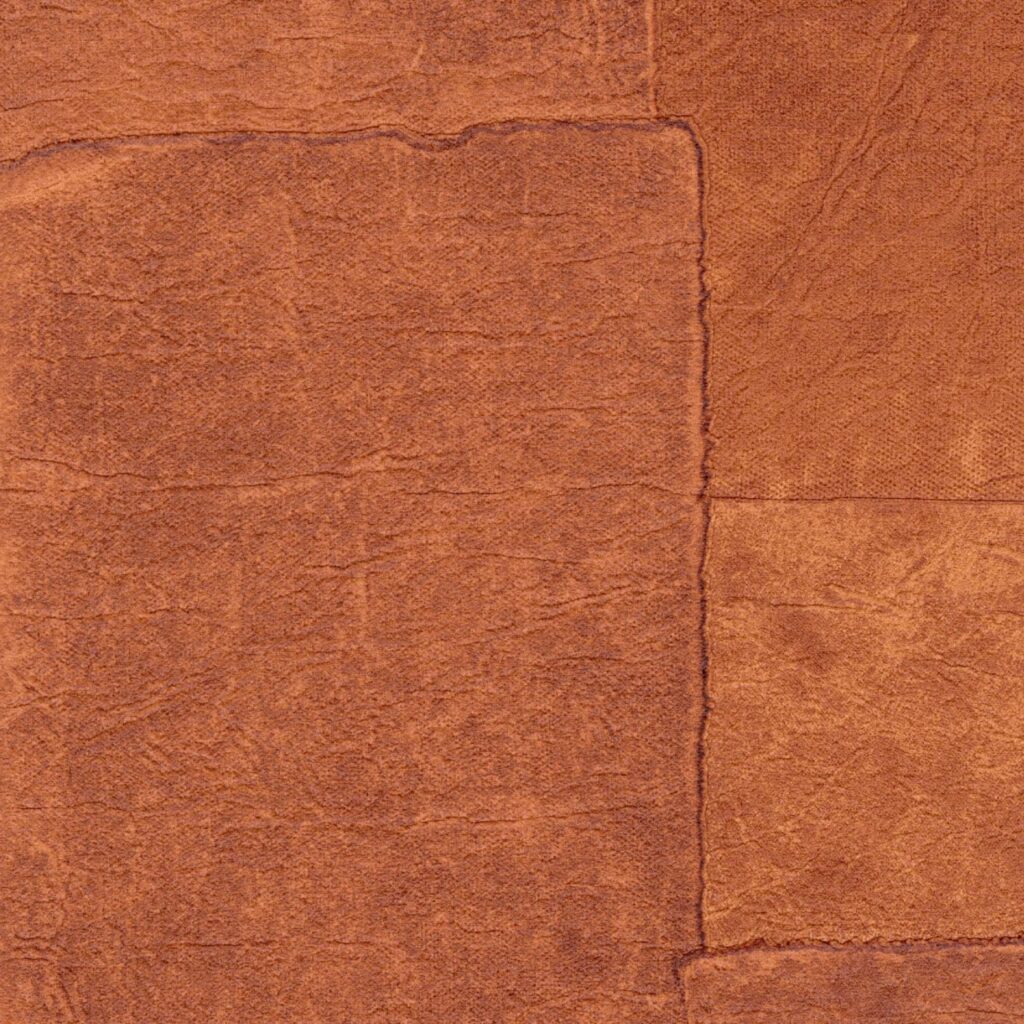 Close-up van Elitis Sangpi VP 1018 35 behang in een warme roestbruine kleur met een patchwork structuur.
