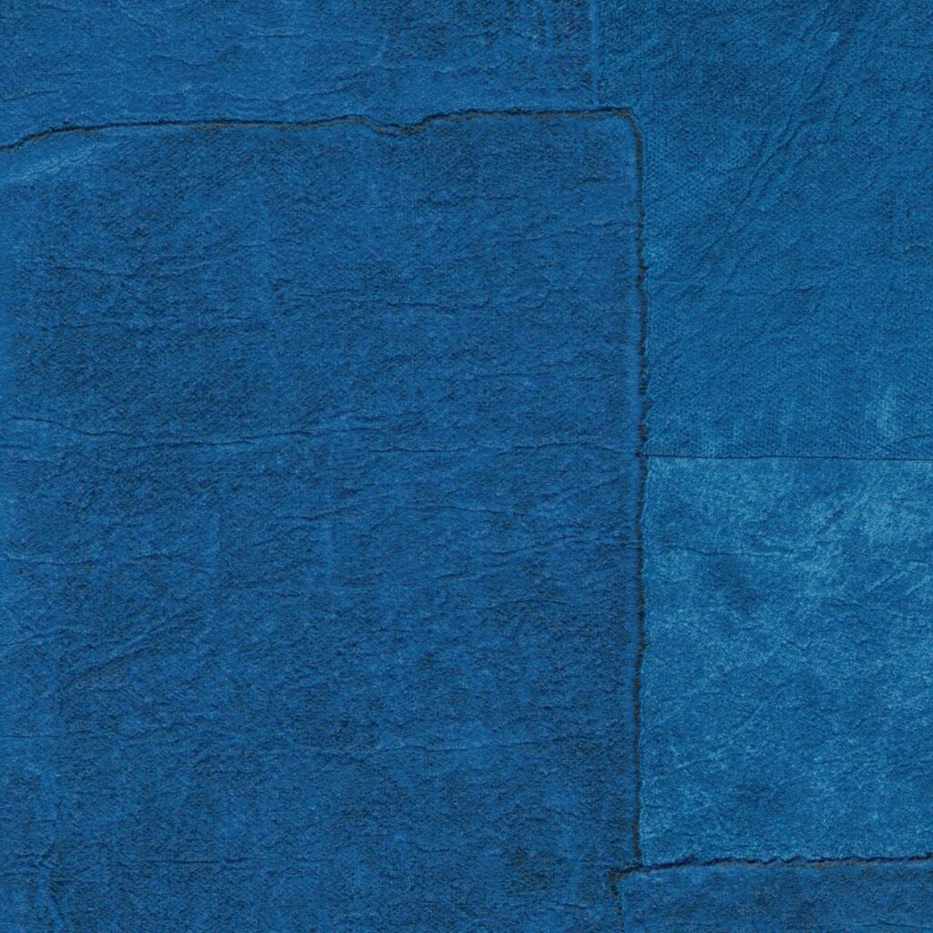Close-up van Elitis Sangpi VP 1018 42 behang met een textuur van verschillende blauw getinte vlakken in patchwork-stijl.