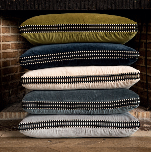 Stapel Elitis sierkussens Athena met passement in verschillende kleuren voor een open haard.