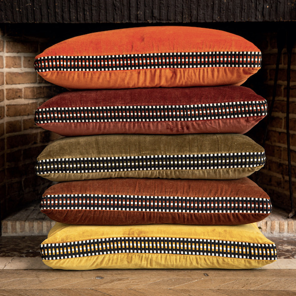 Stapel Elitis sierkussens uit de Athena-collectie in warme roodtinten voor een sfeervol interieur.