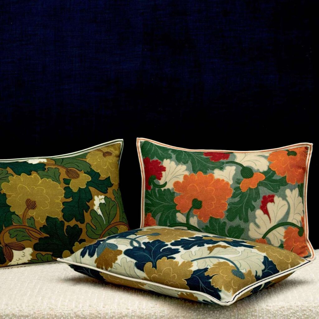Drie Elitis-sierkussens uit de Jane-collectie met kleurrijk bloemenpatroon tegen een donkere achtergrond.