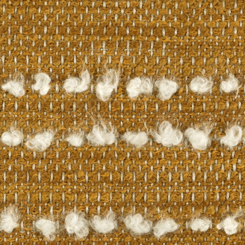 Detail van Elitis-stof Flanerie in geel met witte getufte accenten en grof geweven structuur.