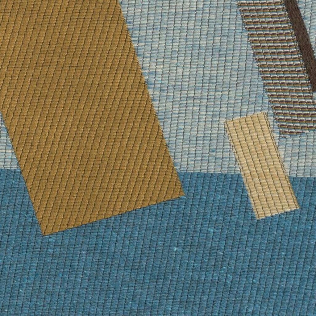 Detail van Elitis-stof Alchimia Corso LR 343 49 met grafische, geweven patronen in blauw, bruin en okergeel.