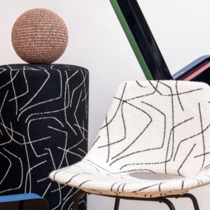 Designstoel en poef bekleed met Elitis Alchimia Scala-stof met abstracte zwarte lijnen op een witte en zwarte achtergrond.