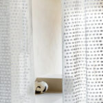 Lichte Elitis-stof Ephemere Ryokan LI 899 01 met geometrisch patroon hangt voor een minimalistisch interieur met een keramische vaas.