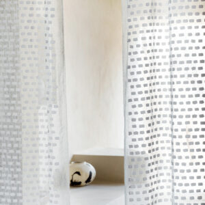 Lichte Elitis-stof Ephemere Ryokan LI 899 01 met geometrisch patroon hangt voor een minimalistisch interieur met een keramische vaas.
