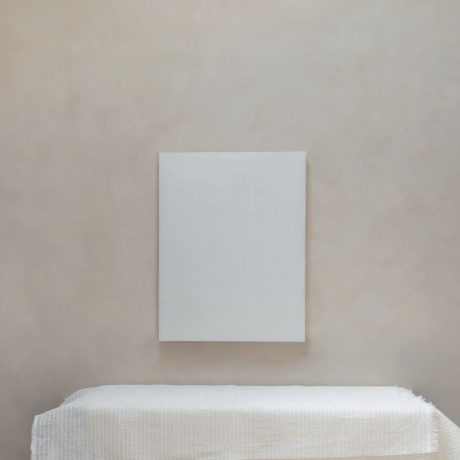 Witte Elitis-stof Ephemere Blancheur Eternelle op een canvas en tafel tegen een neutrale muur.