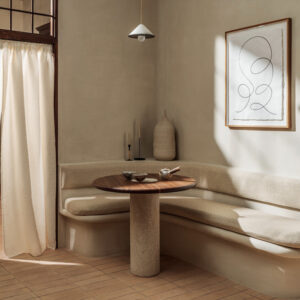 Sfeervol ingerichte hoekzit met Elitis-stof Éphémère Couture LW 910 05, ronde houten tafel en minimalistisch decor in neutrale tinten.