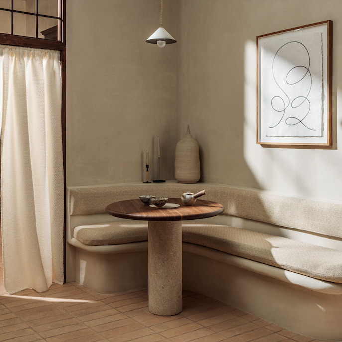 Sfeervol ingerichte hoekzit met Elitis-stof Éphémère Couture LW 910 05, ronde houten tafel en minimalistisch decor in neutrale tinten.