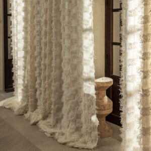 Lichte Elitis Ephemere Patchi Li 901 01 gordijnen met textuur hangen voor een houten deur in een sfeervol interieur.