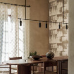 Sfeervolle eetkamer met Elitis Ephemere Patchi Li 901 01 stof, houten meubelen en moderne verlichting.