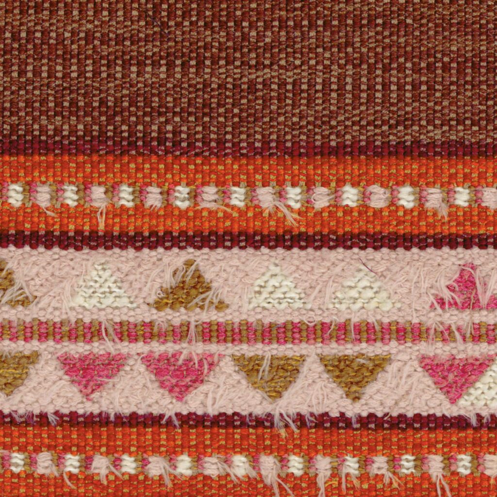 Detailopname van de kleurrijke Elitis-stof Escondido Alma WO 114 35 met geweven patronen in rood, roze, wit en bruin.