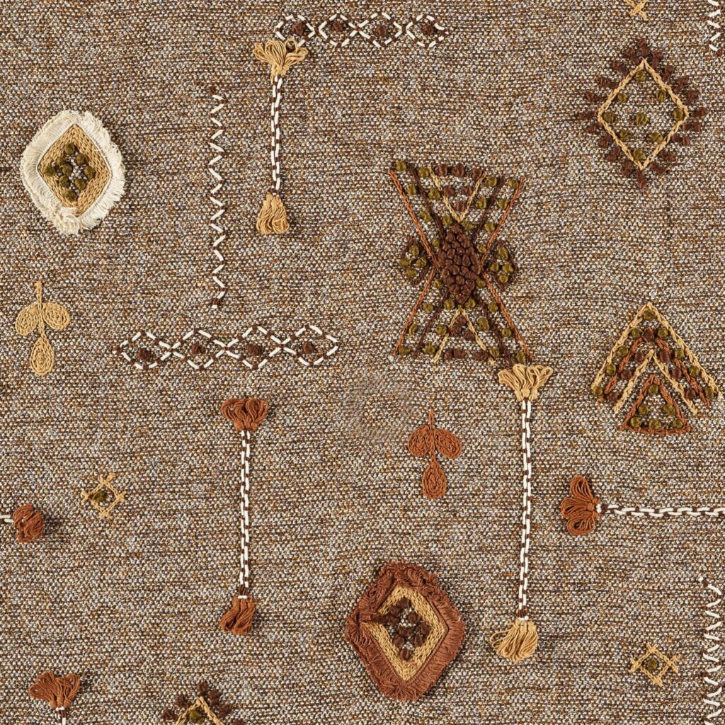 Decoratieve Elitis-stof Loreto LZ 890 22 met etnisch geïnspireerde borduursels in aardetinten op een geweven achtergrond.