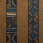Bruin textiel uit de Elitis Escale-collectie met etnisch geïnspireerde, grafische patronen in zwart, blauw en wit.