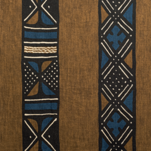 Bruin textiel uit de Elitis Escale-collectie met etnisch geïnspireerde, grafische patronen in zwart, blauw en wit.