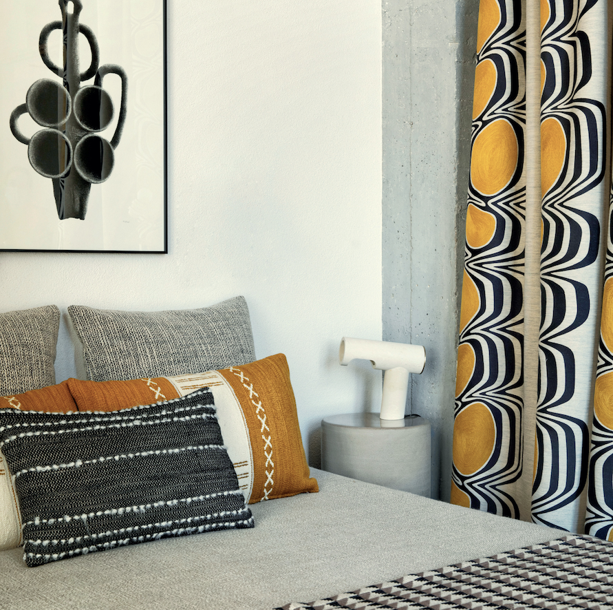 Modern ingerichte slaapkamer met Elitis Escale-gordijnen, grafische kussens en kunst aan de muur.
