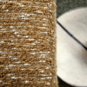 Detail van Elitis-stof Horizon met een grof geweven textuur in bruin en wit.