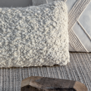 Twee decoratieve Elitis Horizon-kussens in neutrale tinten op een geweven vloerkleed.