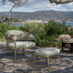 Luxe Elitis outdoor-stoel met bijpassende hocker in een mediterrane tuinsetting met uitzicht op de kust.
