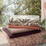 Stapel Elitis outdoor stoffen uit de Rio Pile 2021 collectie met diverse natuurlijke patronen op een stenen vensterbank.