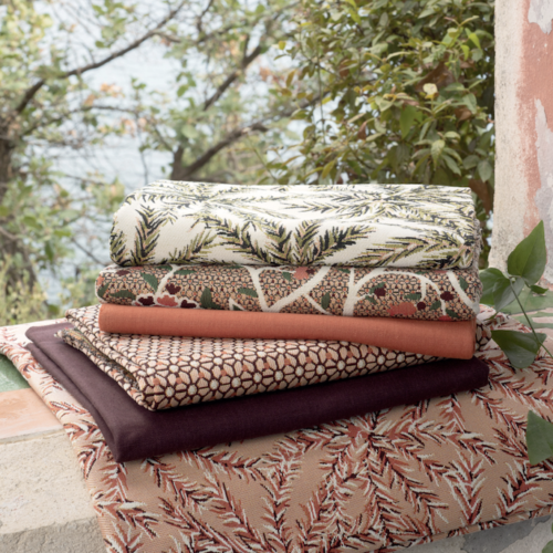 Stapel Elitis outdoor stoffen uit de Rio Pile 2021 collectie met diverse natuurlijke patronen op een stenen vensterbank.