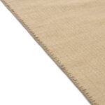 Detailopname van de rand van het beige Elitis Tenere vloerkleed TA 126 04 met zichtbare stiknaden.