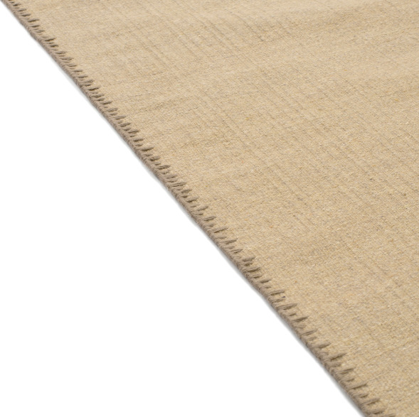 Detailopname van de rand van het beige Elitis Tenere vloerkleed TA 126 04 met zichtbare stiknaden.