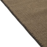 Detailopname van de rand van het Elitis Tenere vloerkleed TA 126 18 met zichtbare stiksels.