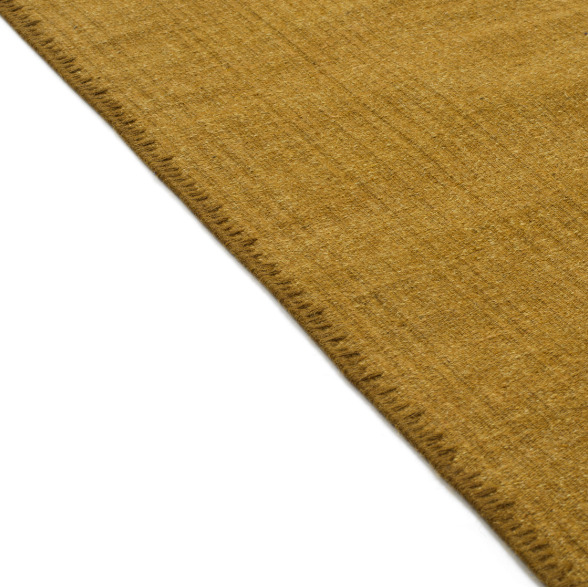 Detailopname van de rand van het Elitis Tenere vloerkleed TA 126 28 in een mosterdgele kleur.